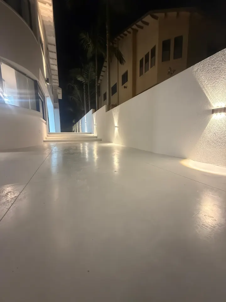תאורת קיר חמה לאורך החצר הצדדית של הוילה בלילה